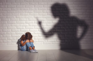  angry mother scolds frightened daughter sitting on floor