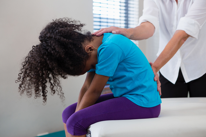 Young girl's back being adjusted by a female chiropractor