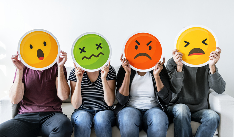 Diverse people holding emoticons over their faces
