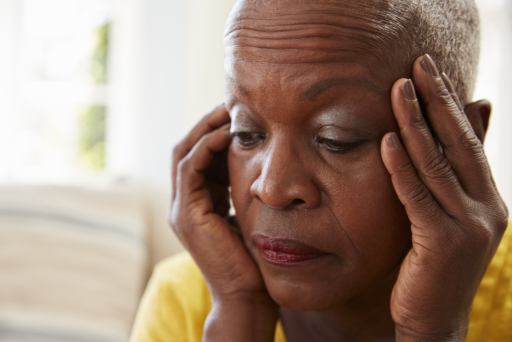 Senior Woman Sitting On Sofa At Home Suffering From Depression