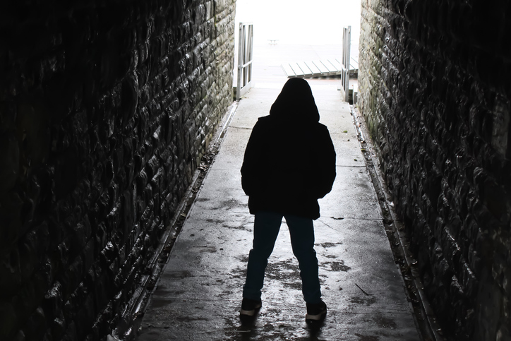 Hooded boy silhouetted in an underground tunnel