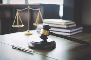 Scales of justice and Gavel on wooden table and Lawyer or Judge working with agreement in Courtroom