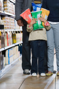 Family in store, child holding packets of potato chips