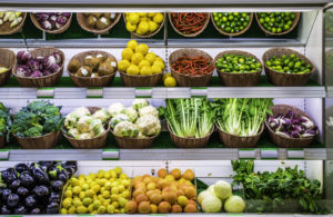 Fruits and vegetables in baskets on a supermarket shelf.