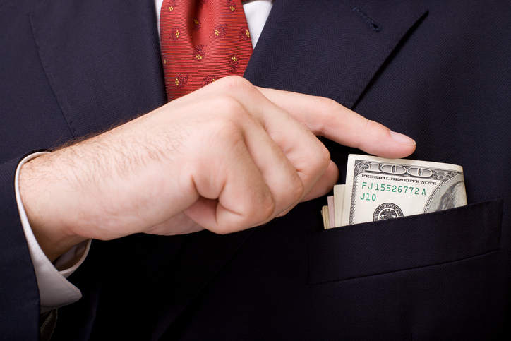 Man in suit putting $100's in boutonniere close up.