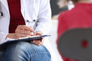 Doctor with clipboard talking to young patient