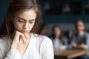 Sad young girl with a secret sitting alone in cafe