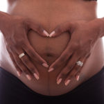 Young beautiful pregnant African-American woman touching her belly