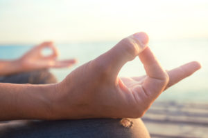 Meditation hand gesture, sitting on the beach in the sun