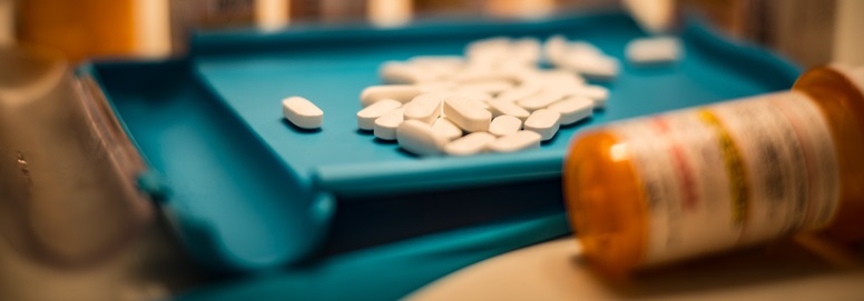 Unsorted prescription pills sit in a pharmacist's counting tray before they are bottled.