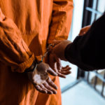 cropped image of prison officer wearing handcuffs on prisoner