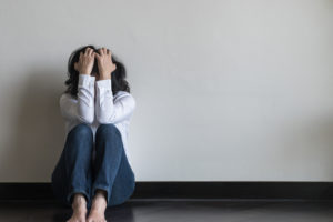 Woman sitting feeling stressed out with back against wall on the floor in home