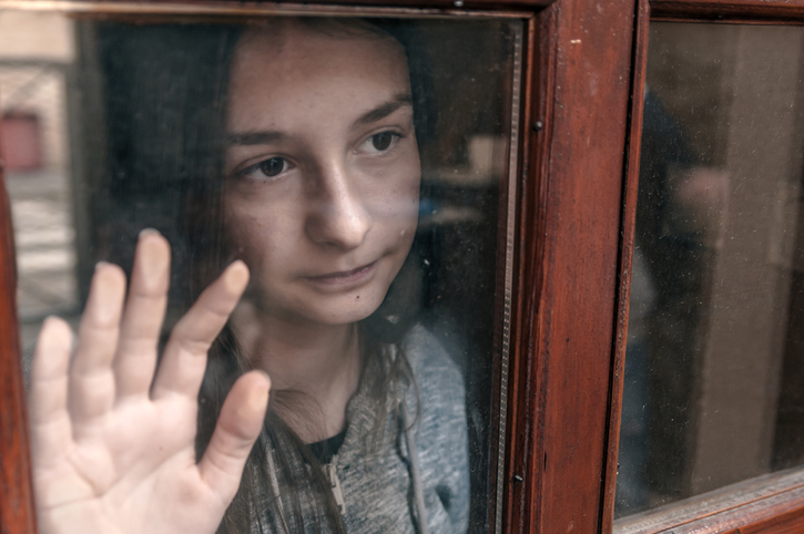 Emotional portrait of a teenage girl looking out window