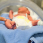 Premature baby in NICU with hand of the doctor