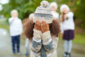 Crying girl hiding her face while classmates mocking at her