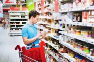 man reading label on the bottle in supermarket