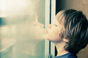 Boy with autism looking through the window