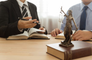 Case manager advising client. Lady justice on law book in law office.