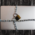 Heavy with a padlock around a laptop isolated on grey table.