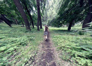 girl running away on path in forest