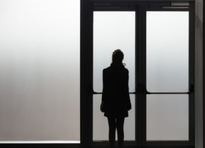 Depressed woman waiting in front a glass door in a white room